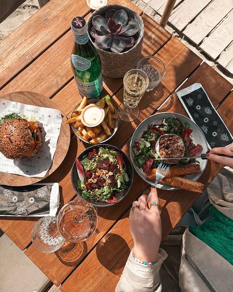 Bovenaanzicht van lunchgerechten op tafel met geitenkaassalade en hamburger